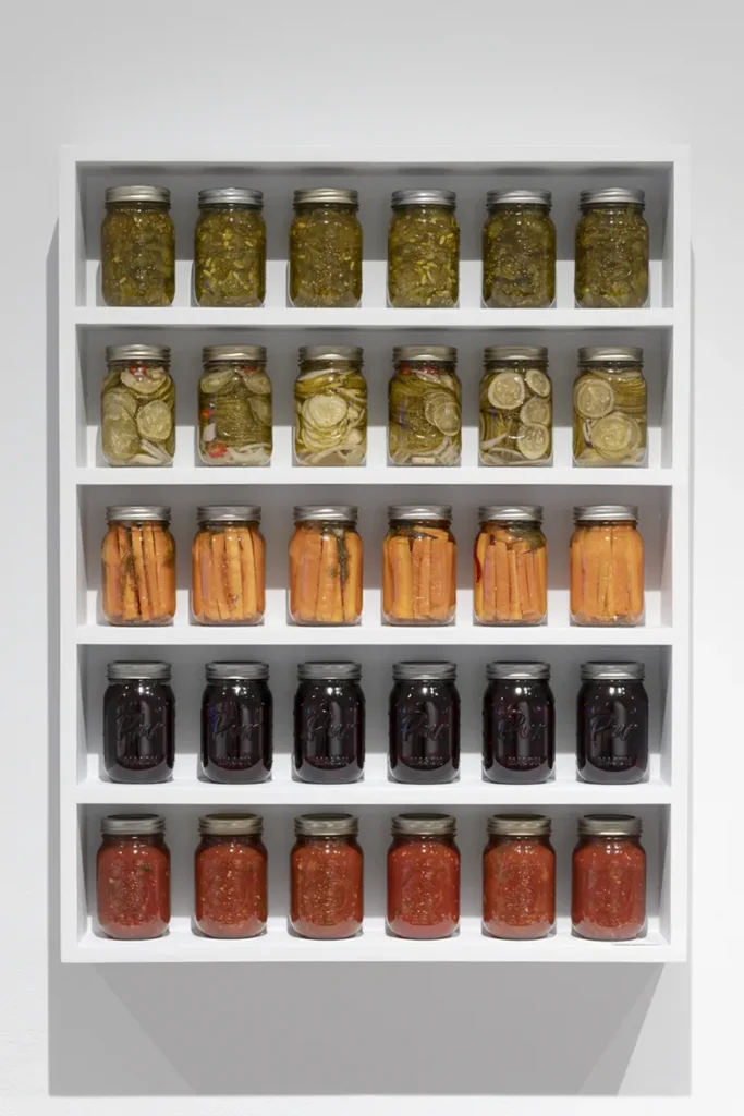 Rows of preserves jars displayed on wall-mounted shelves.